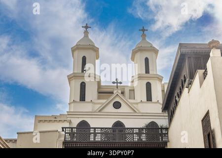 Historische koptische Kirche (St. Jungfrau Maria) mit Doppeltürmen, Kreuzen und traditionellem Gitterbalkon unter blauem Himmel; im koptischen Kairo dist Stockfoto