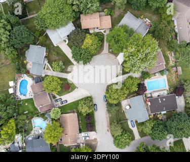 Drohnenantenne einer Sackgasse vor Ort mit Wohnhäusern, von Bäumen gesäumten Straßen und Schwimmbädern im Hinterhof. Stockfoto