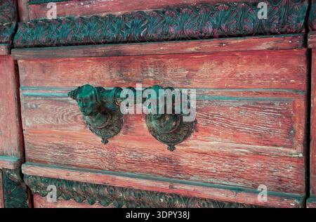 Alte Holztür mit dekorativem Griff mit zwei männlichen Gesichtern (Paris, Frankreich). Getöntes Foto. Stockfoto