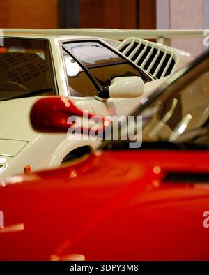 Rechter Seitenspiegel des roten Ferrari 512 TR mit verschwommenem weißem Lamborghini Countach im Hintergrund Stockfoto