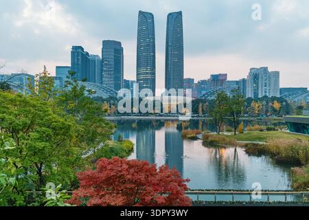 Skyline der Stadt Chengdu mit zwei Türmen, die sich in der Abenddämmerung in einem städtischen See spiegeln, Provinz Sichuan, China. Bürogebäude im Finanzviertel Stockfoto
