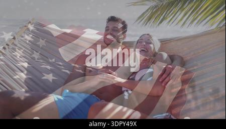 Entspannendes Paar in Hängematte am Strand in Bikinihose und Shorts, Überzug mit amerikanischer Flagge, Palmwedeln Stockfoto