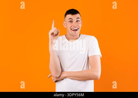Eureka. Aufgeregter junger Kaukasier, der eine ausgezeichnete Idee hat, Inspiration oder Lösung für ein Problem findet, gelber Hintergrund Stockfoto