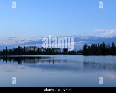 Reflexion von Bäumen und Grand Hotel Gebäuden im Štrbské pleso See, Štrba, Poprad, Prešov, Slowakei, Mai 2024 Stockfoto