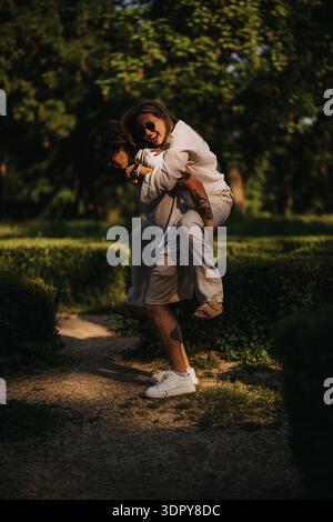 Ein Paar, das an einem sonnigen Tag einen Huckepack-Ritt im Park genießt, ein verspielter und zärtlicher Moment Stockfoto