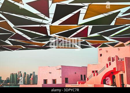 Doha, Katar - 15. januar 2026: Farbenfrohe geometrische Schatteninstallation über dem Mina District Doha mit pastellfarbenen Gebäuden und der Skyline der Stadt, die einen modernen Look schaffen Stockfoto
