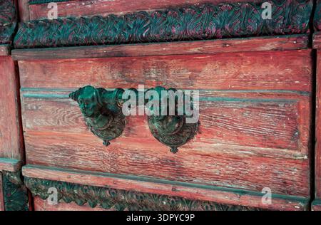 Alte Holztür mit dekorativem Griff mit zwei männlichen Gesichtern (Paris, Frankreich). Getöntes Foto. Stockfoto