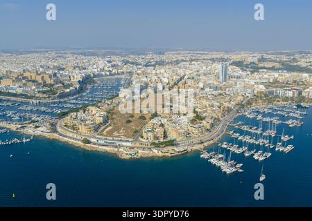 Aus der Vogelperspektive des Yachthafens von Ta' Xbiex in Malta mit Segelbooten und Yachten, die entlang des gekrümmten Hafens unter klarem blauem Himmel vertäut sind. Stockfoto