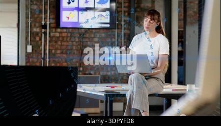 Frau in weißem Oberteil, graue Hose, die im Büro am Laptop arbeitet, blaue AR-Grafik, Kopierraum Stockfoto