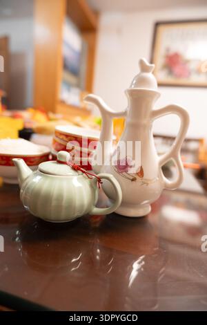 Chinesische Keramik-Teekannen auf poliertem Tisch mit verschwommenem Küchenhintergrund, traditionelles Teeset in häuslicher Umgebung Stockfoto