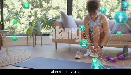 Schnürsenkel für Frauen zu Hause in Activewear mit blauem Matt, Kurzhanteln, AR-Ikonen, Kopierraum Stockfoto