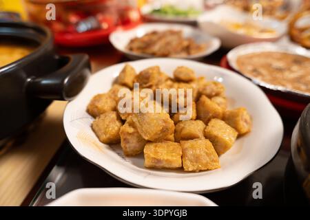 Chinesische Sichuan-Tofu-Gerichte auf weißen Tellern am Esstisch mit verschiedenen Beilagen Stockfoto