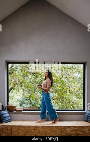 Schöne Frau, die vor einem großen Fenster steht, sauberer Platz. Gewölbedecke oder Kathedraldecke schöne Frau, die vor einem großen Fenster steht, sauber Stockfoto