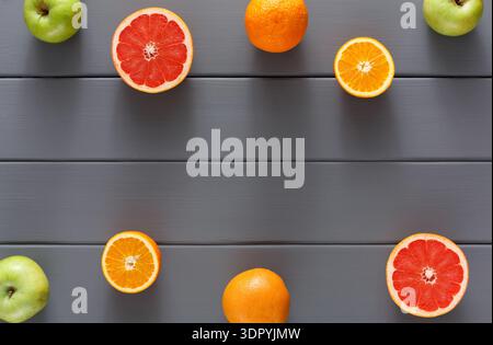 Anordnung verschiedener Zitrusfrüchte und Äpfel auf einer grauen Holzoberfläche in Casual Setup Stockfoto