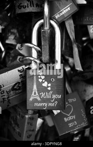 Liebesschloss mit Eiffelturm, Herzen und Heiratsantrag an der Brücke. Paris, Frankreich. Romantisches Urlaubskonzept. Schwarzweißes historisches Foto Stockfoto