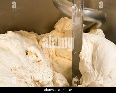 Hausgemachte Brotteigkugeln auf einem Backblech und Teigkneten in einem Mixer. Stockfoto