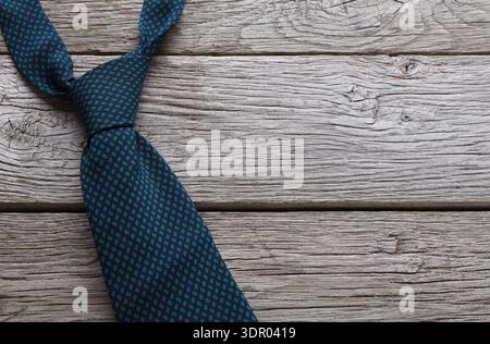 Dunkelblaue Krawatte gefaltet auf Holzoberfläche mit strukturiertem Hintergrund während des ruhigen Moments Stockfoto
