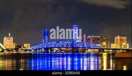 Main Street Bridge in Jacksonville Florida bei Nacht. Historische blau beleuchtete vertikale Liftbrücke überspannt den St. Johns River mit der beleuchteten Skyline der Innenstadt im Hintergrund Stockfoto