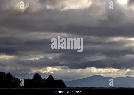 Dunkle Sturmwolken über dem See Taupō mit weit entfernten Hügeln in Silhouette, Taupō, Nordinsel, Neuseeland. Stockfoto