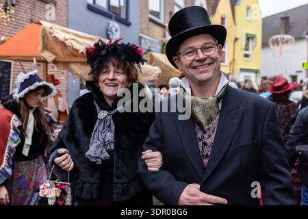 Deventer, Overijssel, Niederlande - 14.12.2025: Zwei Personen in viktorianischen Kostümen spazieren durch eine geschmückte Straße während einer feierlichen öffentlichen Veranstaltung. Stockfoto