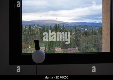 Regen auf einem Schlafzimmerfenster mit Blick auf die Landschaft und die Hügel in der Nähe von Valbonne, Provence-Alpes-Côte d'Azur, Südfrankreich. Stockfoto
