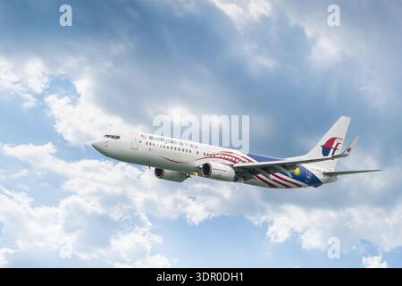Phuket Thailand 12 02 2025: Ein Flugzeug der Malaysia Airlines Boeing 737-8H6 in einer speziellen Malaysia Negaraku Lackierung fliegt gegen die Wolken. Speziell Stockfoto