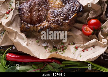 Saftiges Fleischgericht mit frischem Gemüse und Gewürzen auf einem Holztisch Stockfoto