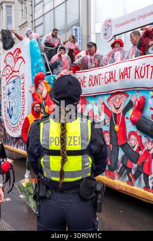 Rosenmontagszug in Düsseldorf, Einsatzkräfte, sichern, begleiten den Umzug, Polizistin mit geschenkten Blumen Sträußchen, Strüsschen, bei teils starkem Regen, NRW, Deutschland Rosenmontag DUS *** Rosenmontag Parade in Düsseldorf, Rettungsdienste, sicher, begleiten die Parade, Polizistin mit Blumensträußen, Sträußchen, bei teils starkem Regen, NRW, Deutschland Rosenmontag DUS Stockfoto