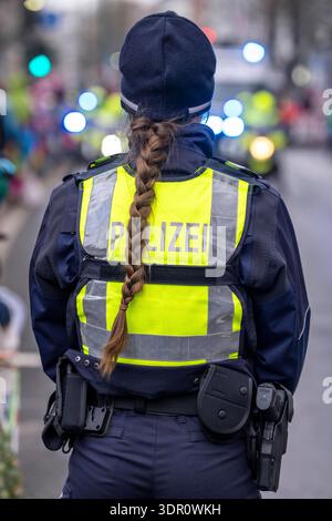 Rosenmontagszug in Düsseldorf, Einsatzkräfte, sichern, begleiten den Umzug, Polizistin mit geschenkten Blumen Sträußchen, Strüsschen, bei teils starkem Regen, NRW, Deutschland Rosenmontag DUS *** Rosenmontag Parade in Düsseldorf, Rettungsdienste, sicher, begleiten die Parade, Polizistin mit Blumensträußen, Sträußchen, bei teils starkem Regen, NRW, Deutschland Rosenmontag DUS Stockfoto