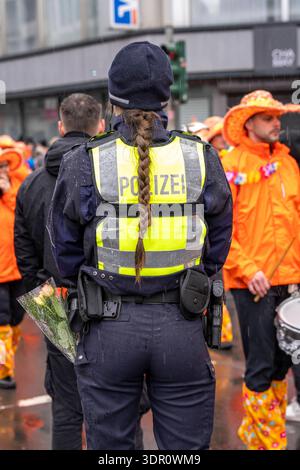 Rosenmontagszug in Düsseldorf, Einsatzkräfte, sichern, begleiten den Umzug, Polizistin mit geschenkten Blumen Sträußchen, Strüsschen, bei teils starkem Regen, NRW, Deutschland Rosenmontag DUS *** Rosenmontag Parade in Düsseldorf, Rettungsdienste, sicher, begleiten die Parade, Polizistin mit Blumensträußen, Sträußchen, bei teils starkem Regen, NRW, Deutschland Rosenmontag DUS Stockfoto