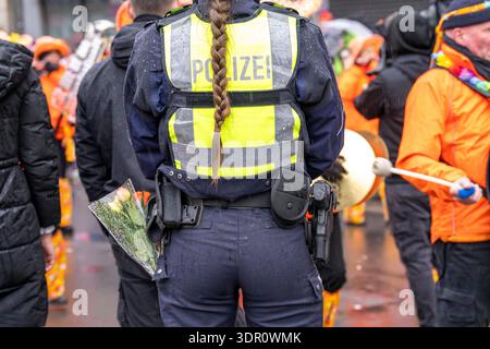 Rosenmontagszug in Düsseldorf, Einsatzkräfte, sichern, begleiten den Umzug, Polizistin mit geschenkten Blumen Sträußchen, Strüsschen, bei teils starkem Regen, NRW, Deutschland Rosenmontag DUS *** Rosenmontag Parade in Düsseldorf, Rettungsdienste, sicher, begleiten die Parade, Polizistin mit Blumensträußen, Sträußchen, bei teils starkem Regen, NRW, Deutschland Rosenmontag DUS Stockfoto