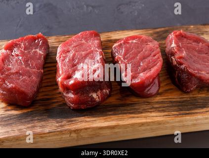 Stücke von rohem Rindfleisch auf einem Holzbrett, bereit zum Kochen und Zubereiten Stockfoto