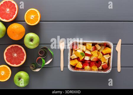 Obstteller mit gemischten Früchten und Besteck auf einer grauen Tischplatte Stockfoto