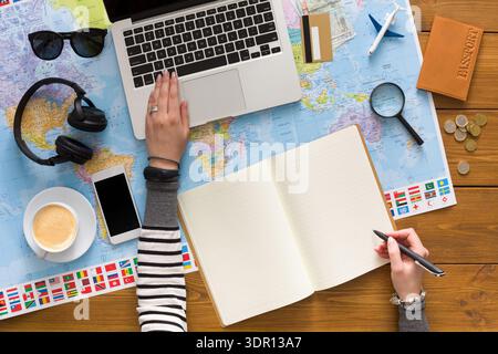 Planen Sie einen Ausflug mit Laptop und Karte auf einem Holztisch am Morgen Stockfoto