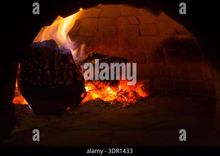 Brennholz brennt in einem Backofen mit glühenden Flammen und heißer Glut Stockfoto