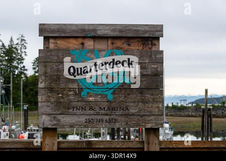 Port Hardy, BC, Kanada - 25. Juni 2024: Das hölzerne Quarterdeck Marina-Schild steht am Ufer, seine rustikale Textur wird vom umliegenden marin eingerahmt Stockfoto