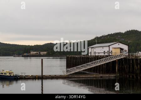 Port Hardy, BC Kanada - 25. Juni 2024: Der Seagate Pier erstreckt sich unter einem bewölkten Himmel mit seinem Pier-Gebäude, einem angedockten Boot und einem Schwimmplan Stockfoto