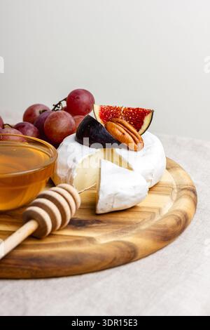 Vorspeisenbrett mit Fleisch, Käse, Trauben, Nüssen, Honig und frischen Feigen. Charcuterie-Teller auf einer beigen Leinentischdecke. Stockfoto