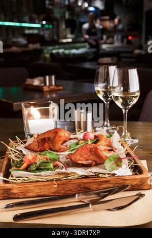 Köstliche Mahlzeit auf Holztablett mit Salat und Getränken in modernem Restaurant Stockfoto