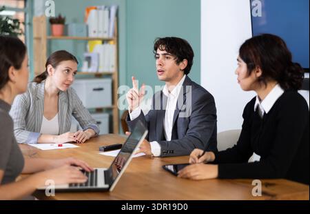 Mann spricht mit jungen Kollegen im Büro Stockfoto