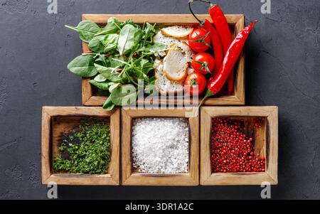 Frisches Gemüse und Kräuter auf einem Holztablett mit verschiedenen Gewürzen in einer Küche Stockfoto