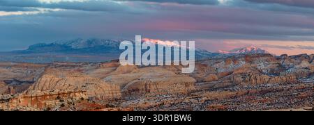 Dieses atemberaubende Winterpanorama des Capitol Reef National Park bietet die Waterpocket Fold mit den Henry Mountains und rosa leuchtenden Wolken bei Sonnenuntergang. Stockfoto