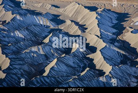 Die blau-grauen Töne der mondähnlichen erodierten Tonhügel in den Caineville Badlands sind auf der Nordseite, die im Schatten liegt, noch immer mit Schnee bedeckt. Stockfoto