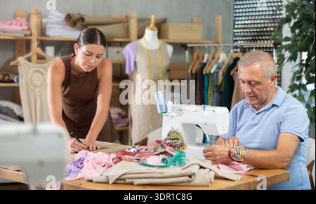 Ein älterer Mann näht weibliche Assistentin auf Papier Stockfoto