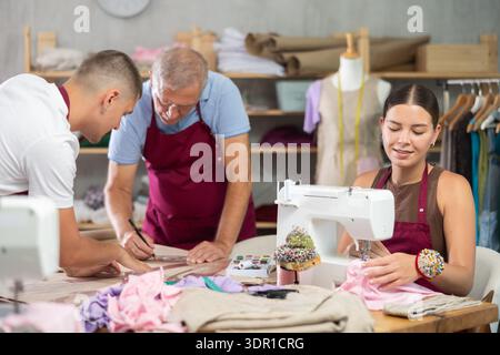 Männliche Schneider zeichnen zusammen eine Skizze neben einer Schneiderin Stockfoto