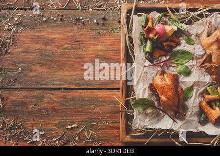 Köstliches Gericht mit gebratenem Huhn, serviert mit Gemüse auf einem Holztisch in einer rustikalen Umgebung Stockfoto