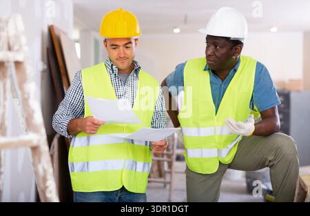 Bauherren mit Gespräch über den Arbeitsplan in der Wohnung Stockfoto