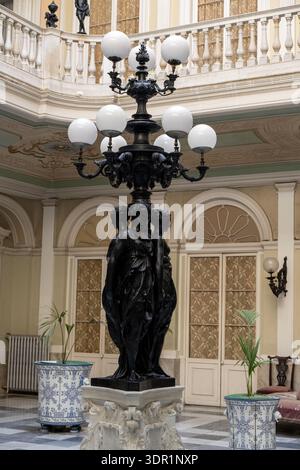 Cadiz, Spanien - 26. September 23: Kunstvoll verzierte gusseiserne Lampenpfosten mit Skulpturen und Globus-Lichtern in einem historischen Atrium-Innenhof in Cádiz, Andalusien, Sp Stockfoto