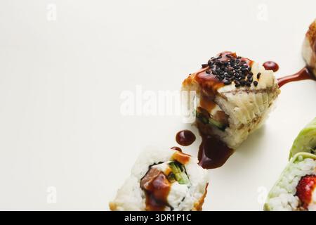 Sushi-Brötchen auf einer flachen Oberfläche mit Sauce und Toppings Stockfoto