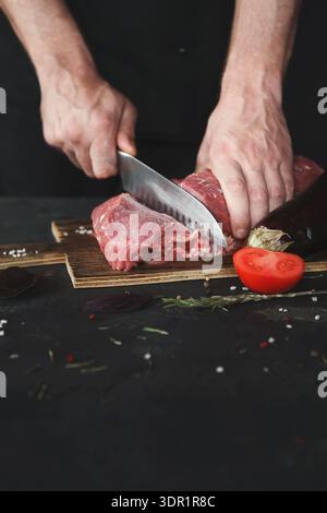 Schneiden von Fleisch und Gemüse auf einem Holzbrett in einer Küche Stockfoto